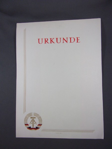 Urkunde blanko Schrift ist in rot links und unten sind 3 goldene Streifen links unten in der Ecke ist das Wappen der DDR  