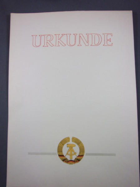 Urkunde blanko Schrift in rot am unteren Rand sind graue Linien und mittig das Wappen der DDR